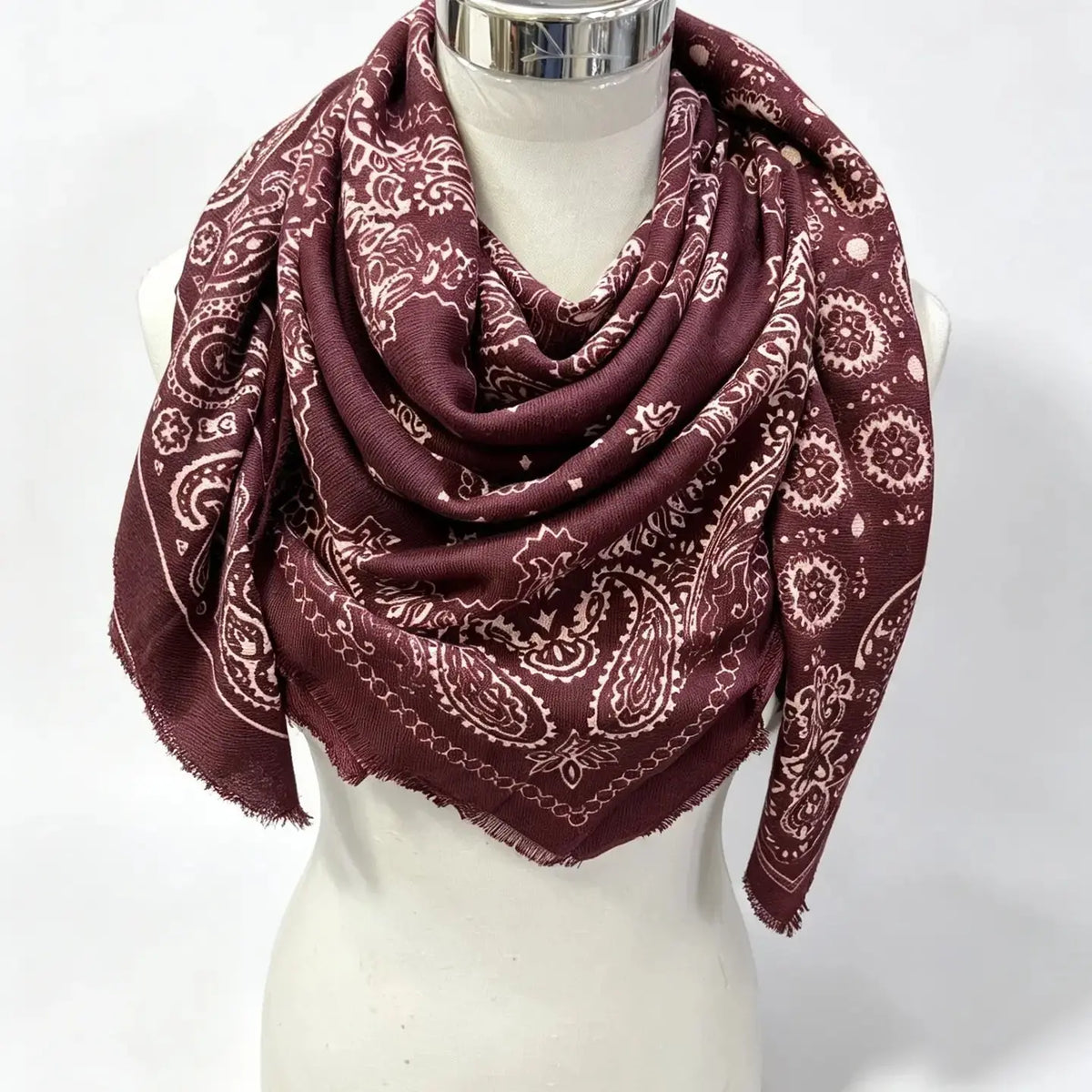 Burgundy paisley bandana with cream pattern, draped on a mannequin with fringed edges visible