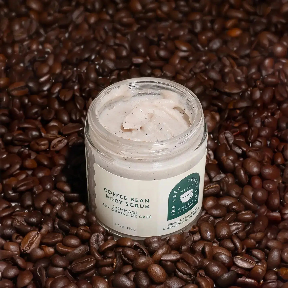 Midnight Paloma Coffee Bean Body Scrub in a jar with coffee beans and natural ingredients, showcasing its exfoliating texture.