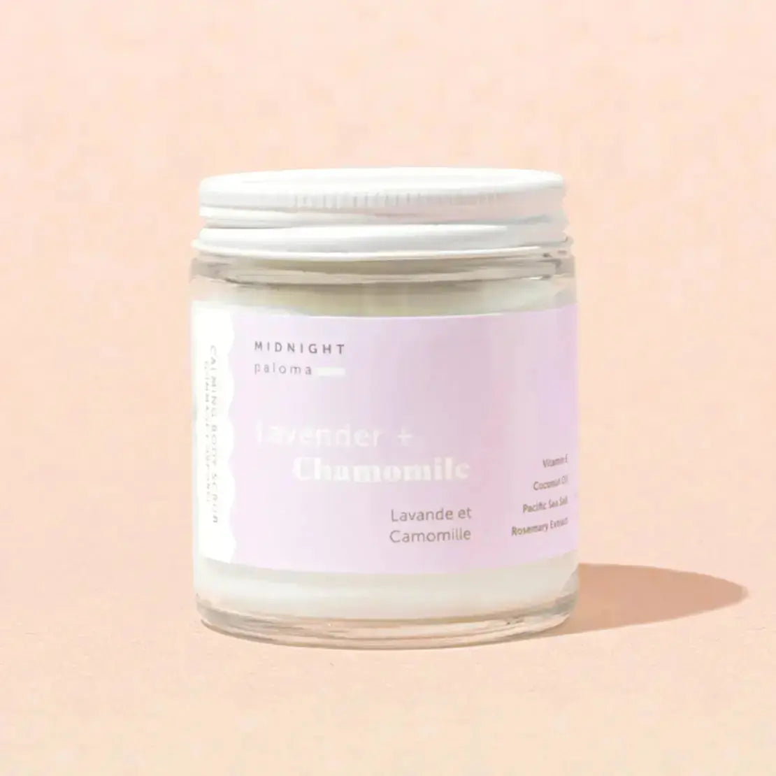 Lavender and chamomile body scrub by Midnight Paloma with a jar of exfoliating scrub and natural ingredients in a clear container.