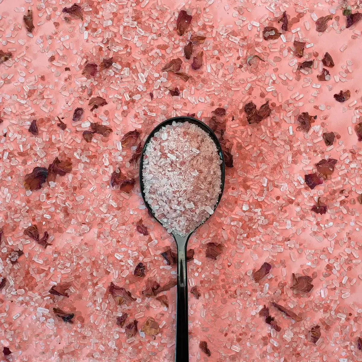 Handmade bath soaks with French rose and vanilla scents from Midnight Paloma, shown in a clear jar with pink and white bath salts.