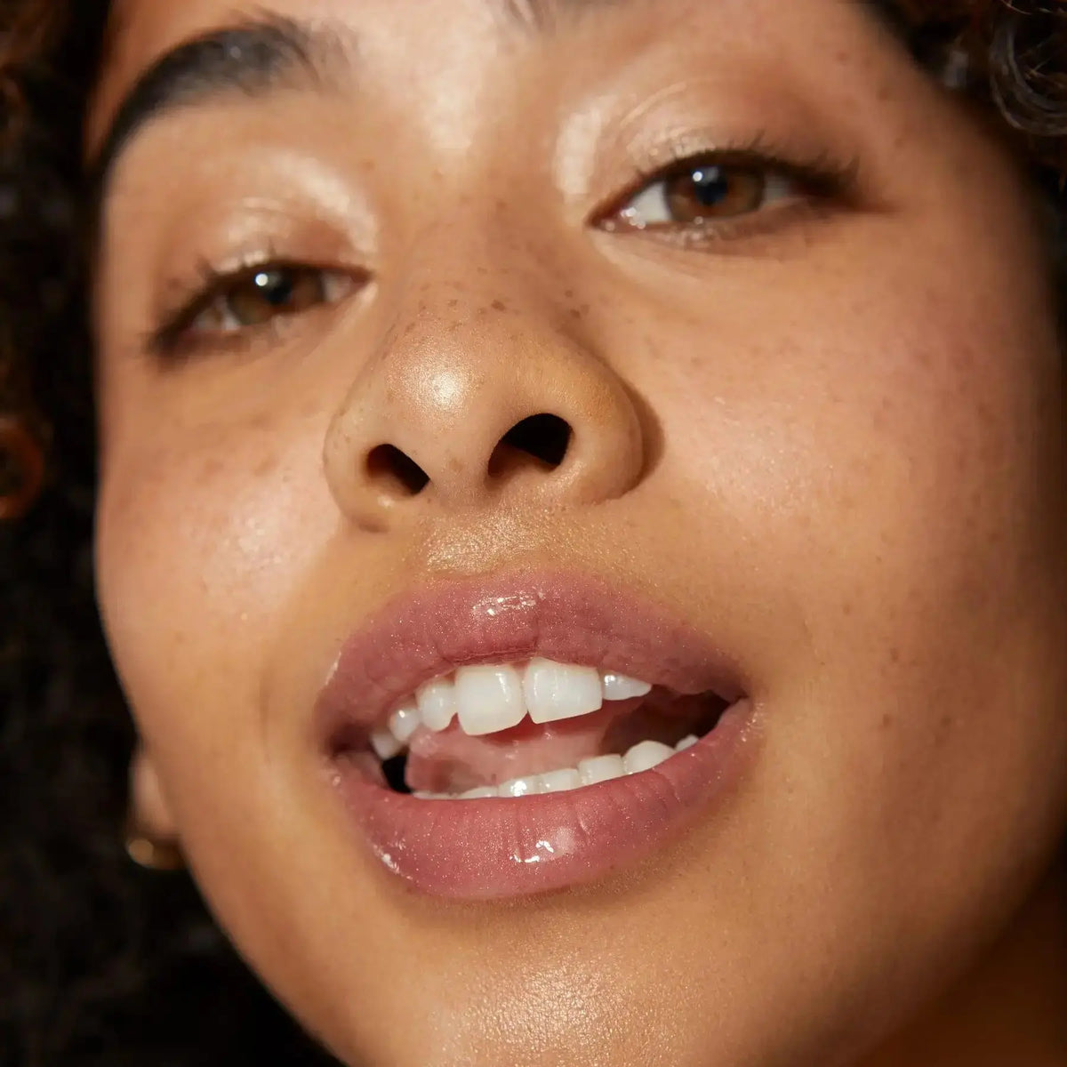 Minori Ultra-Hydrating Vegan Lip Gloss in a clear tube with a shiny finish, showcasing glossy lips and vibrant color.