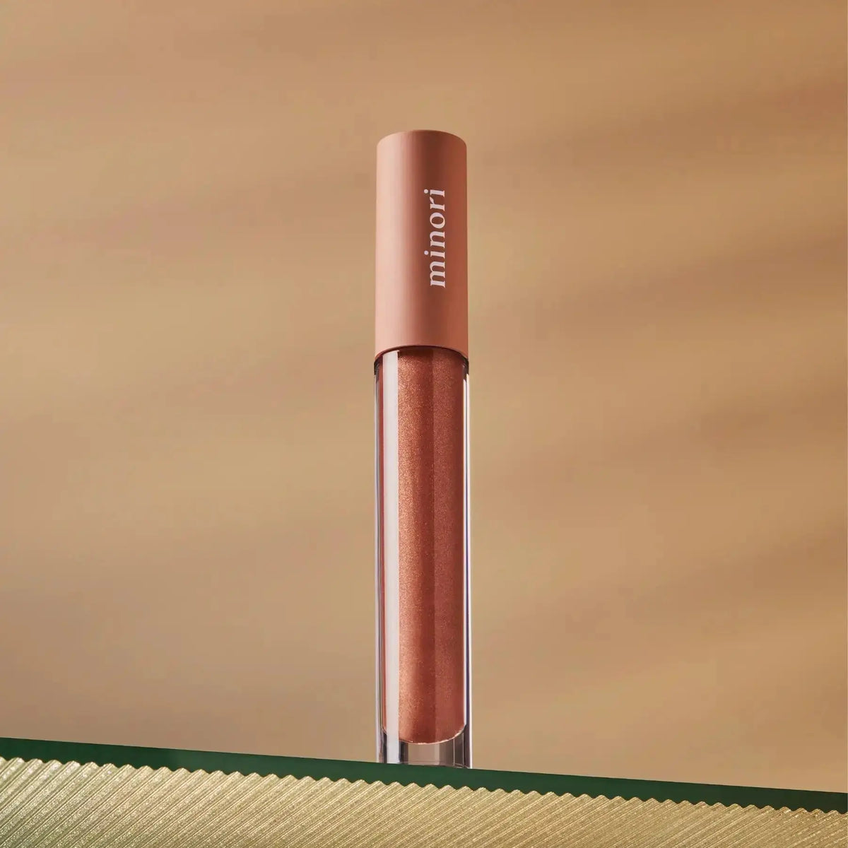 Minori Ultra-Hydrating Vegan Lip Gloss in a clear tube with a shiny, glossy finish, showcasing smooth, hydrated lips.